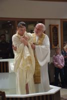 Two clergy in white robes holding a baby at the church altar
