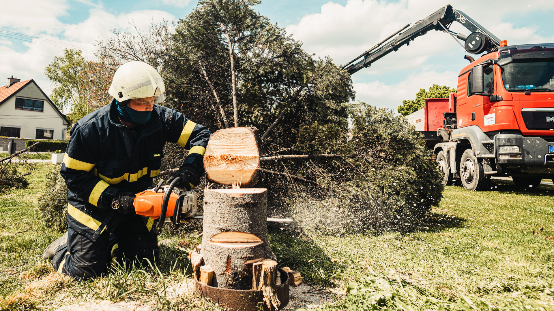 A fireman is cutting a tree stump with a chainsaw.