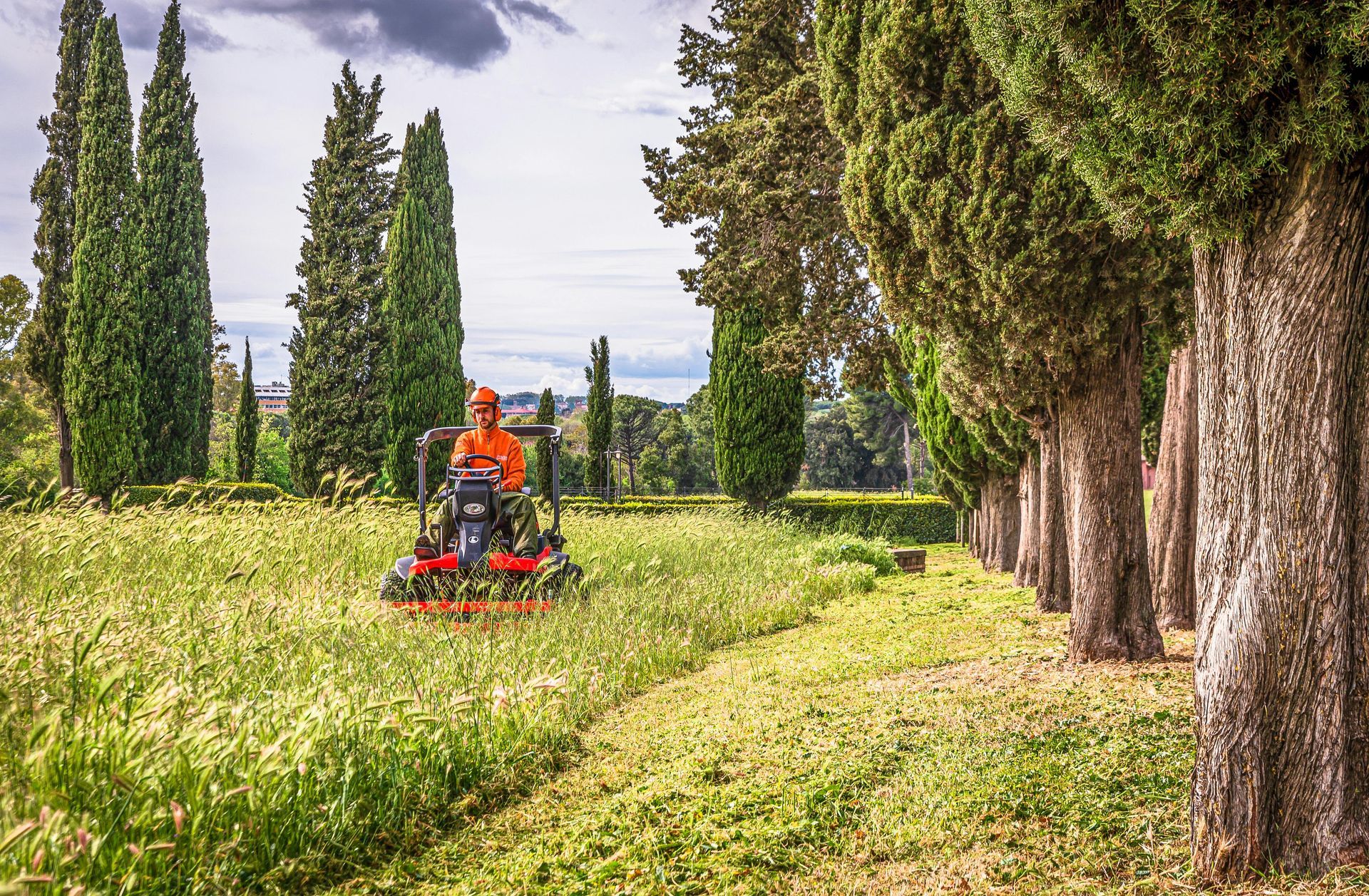 A man is riding a lawn mower through a grassy field.