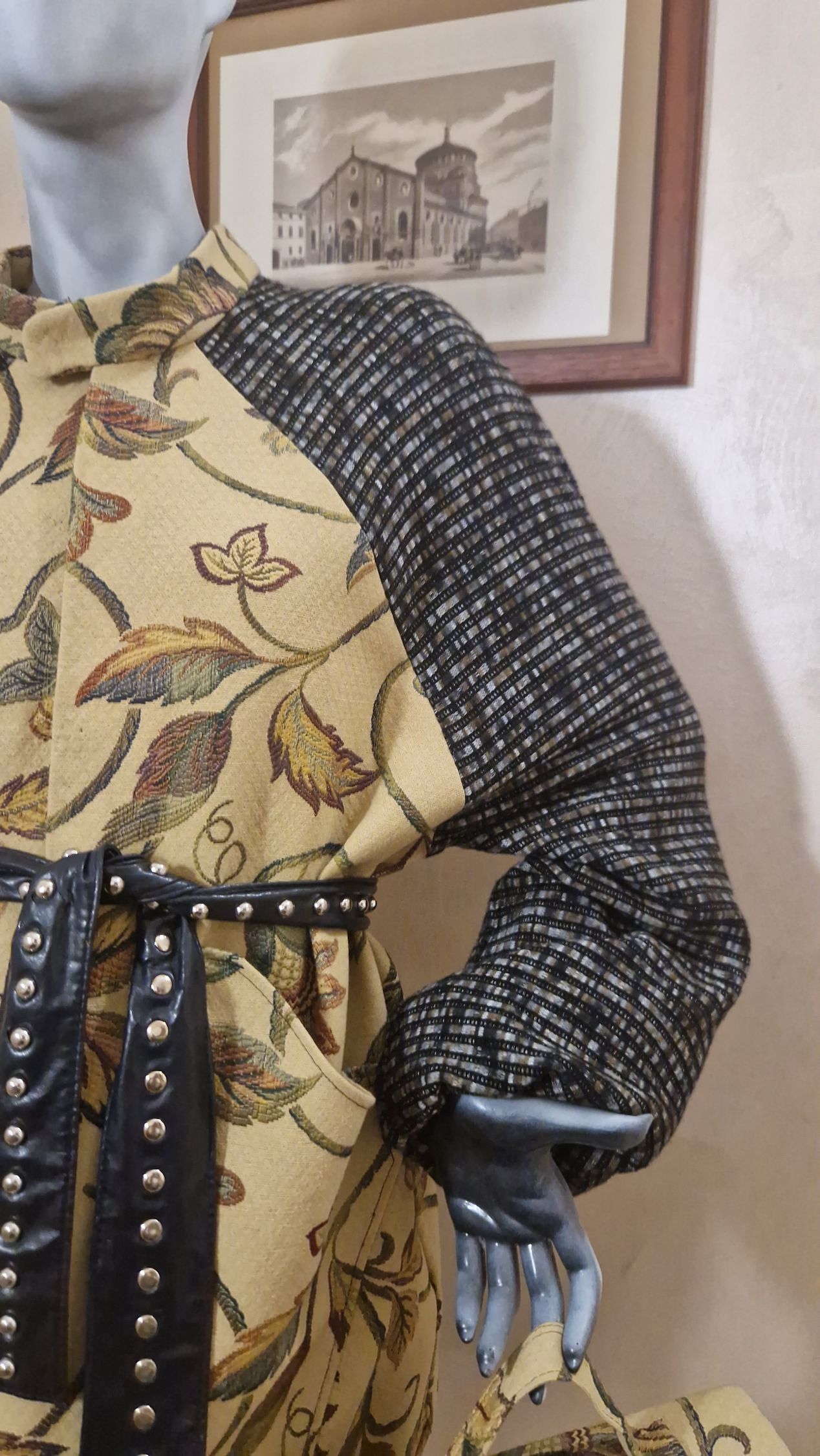 Un manichino indossa un abito floreale e tiene in mano una borsa.