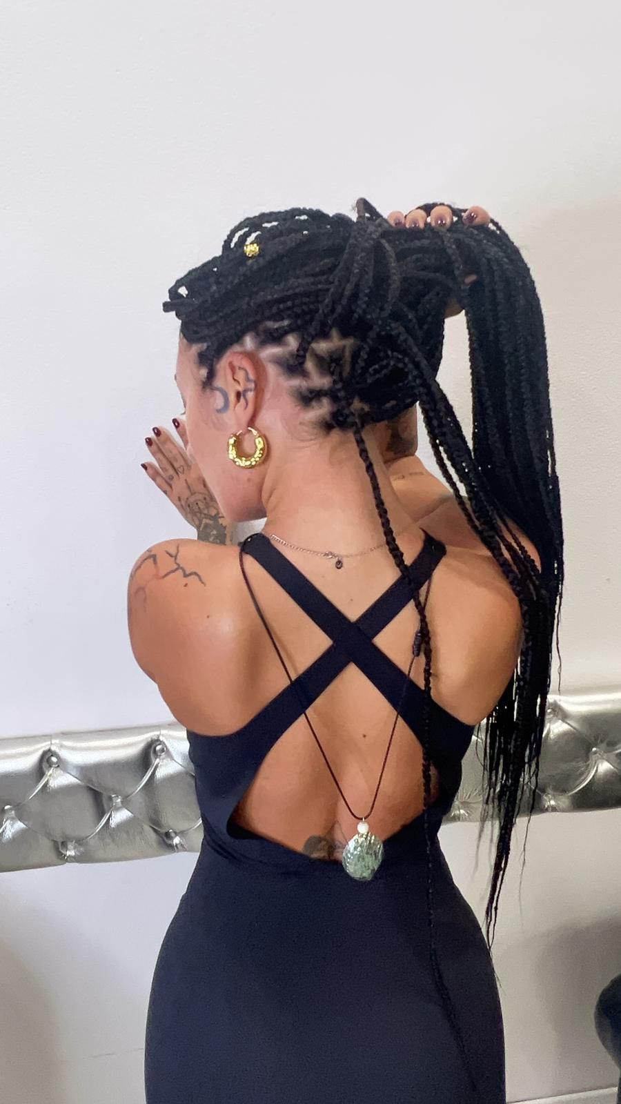 Una donna con i dreadlock indossa un vestito nero con la schiena incrociata.