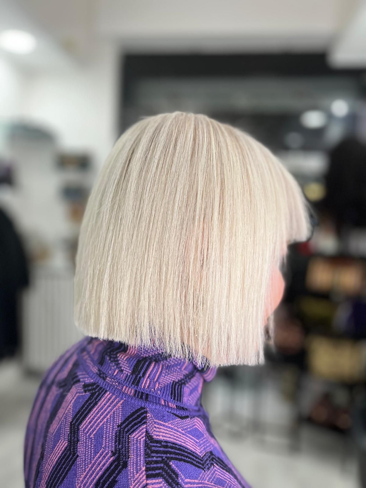 Una donna con i capelli biondi indossa una maglietta viola.