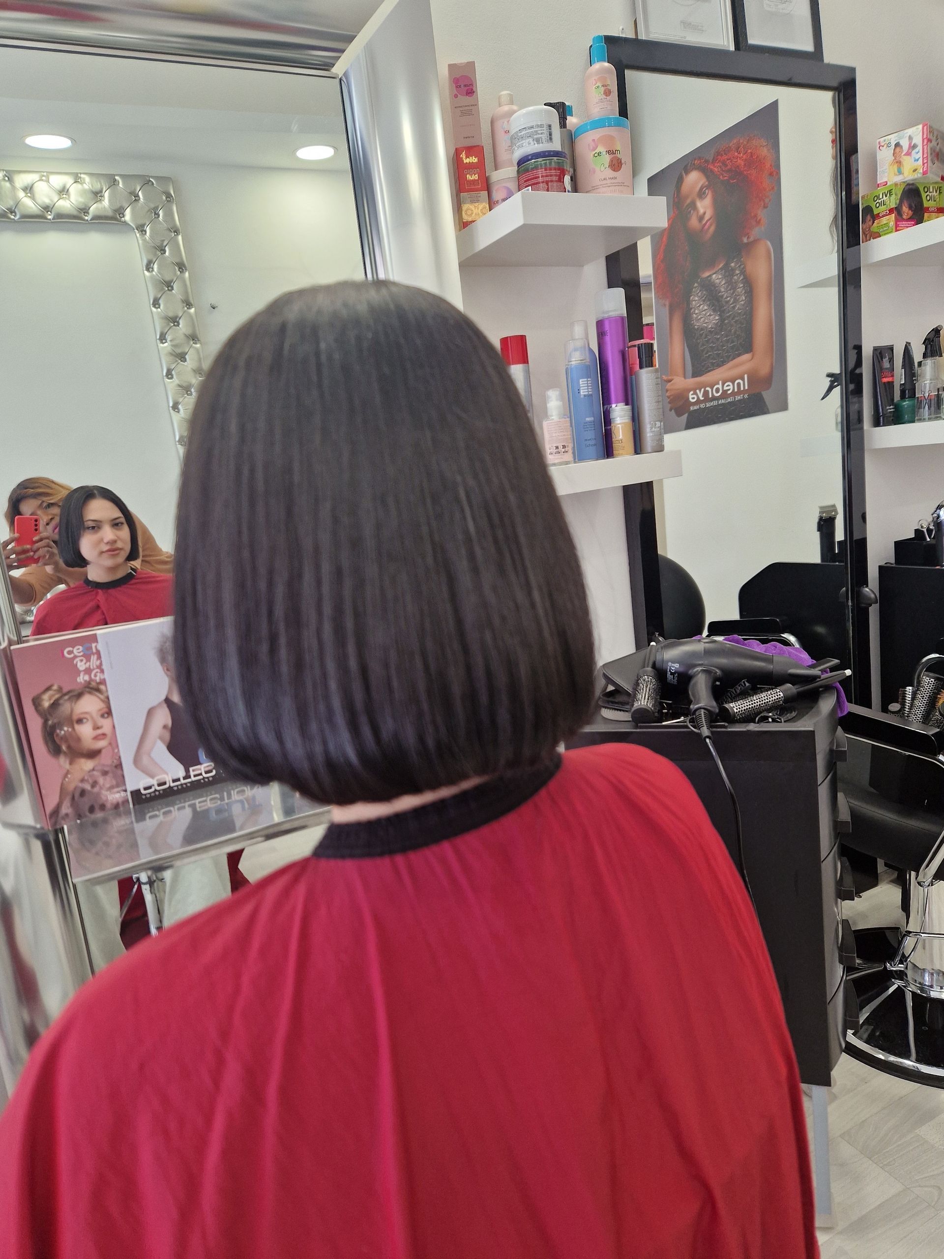 Una donna con un mantello rosso si sta tagliando i capelli in un salone.
