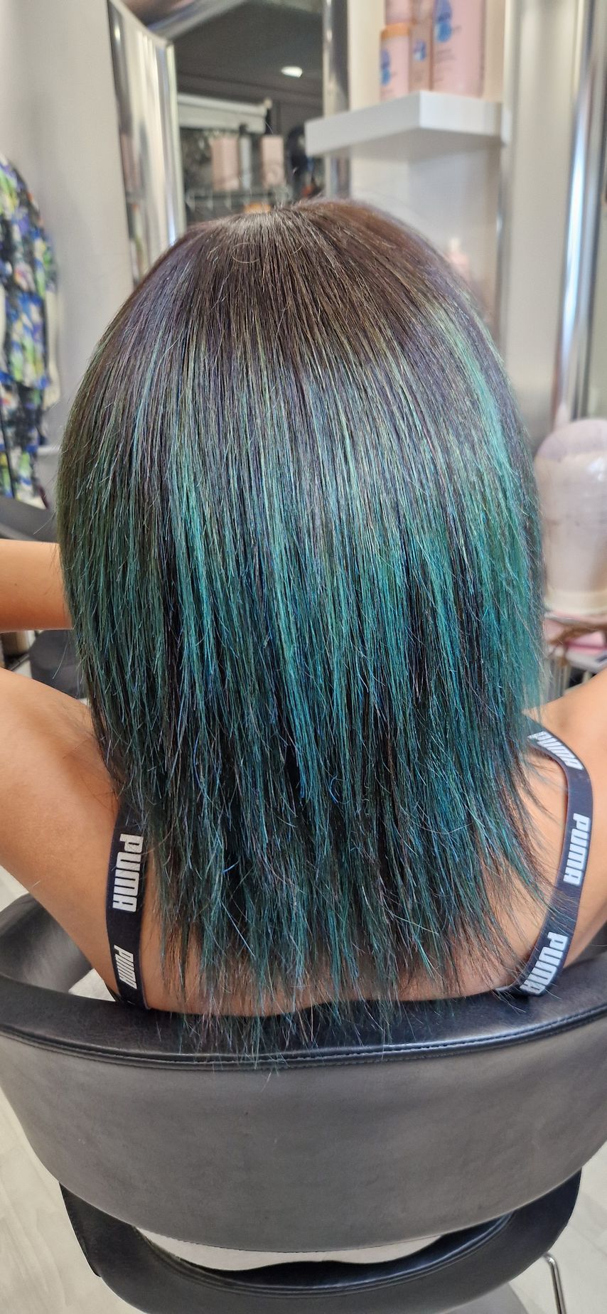 Una donna con i capelli blu è seduta su una sedia in un salone.