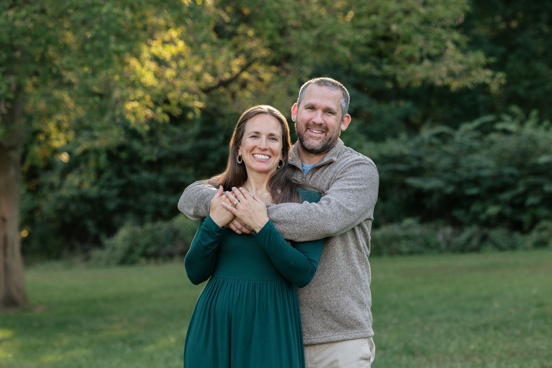 Smiling couple posing close together outdoors, wearing casual clothes and hats.