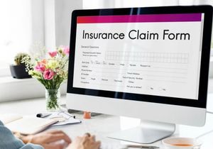 Computer screen displaying an insurance claim form in a bright office desk setting