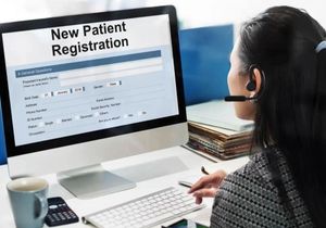 Woman wearing headset entering new patient registration on a desktop computer