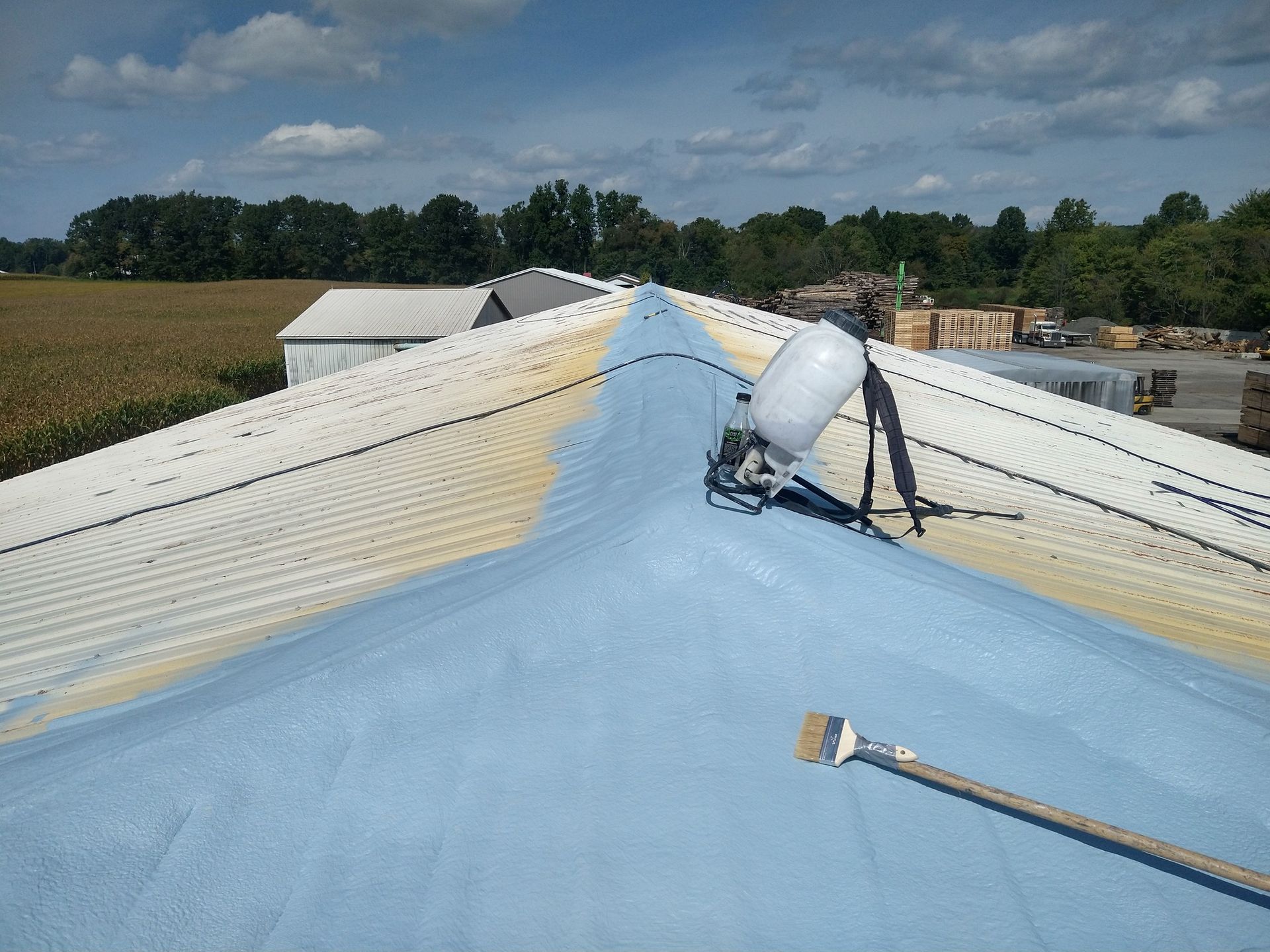A roof is being sprayed with blue foam.