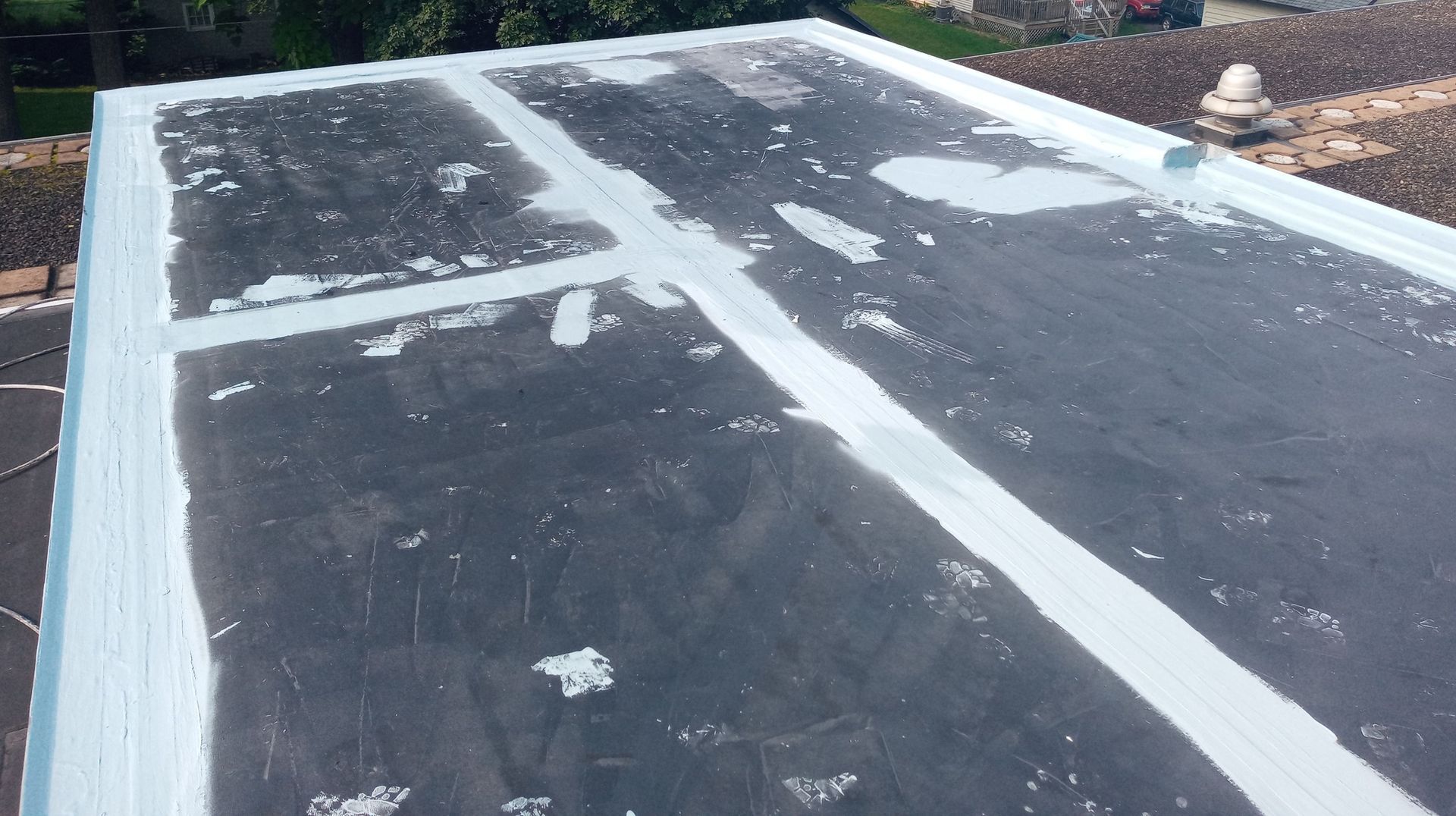 A black roof with white tape on it is being painted.