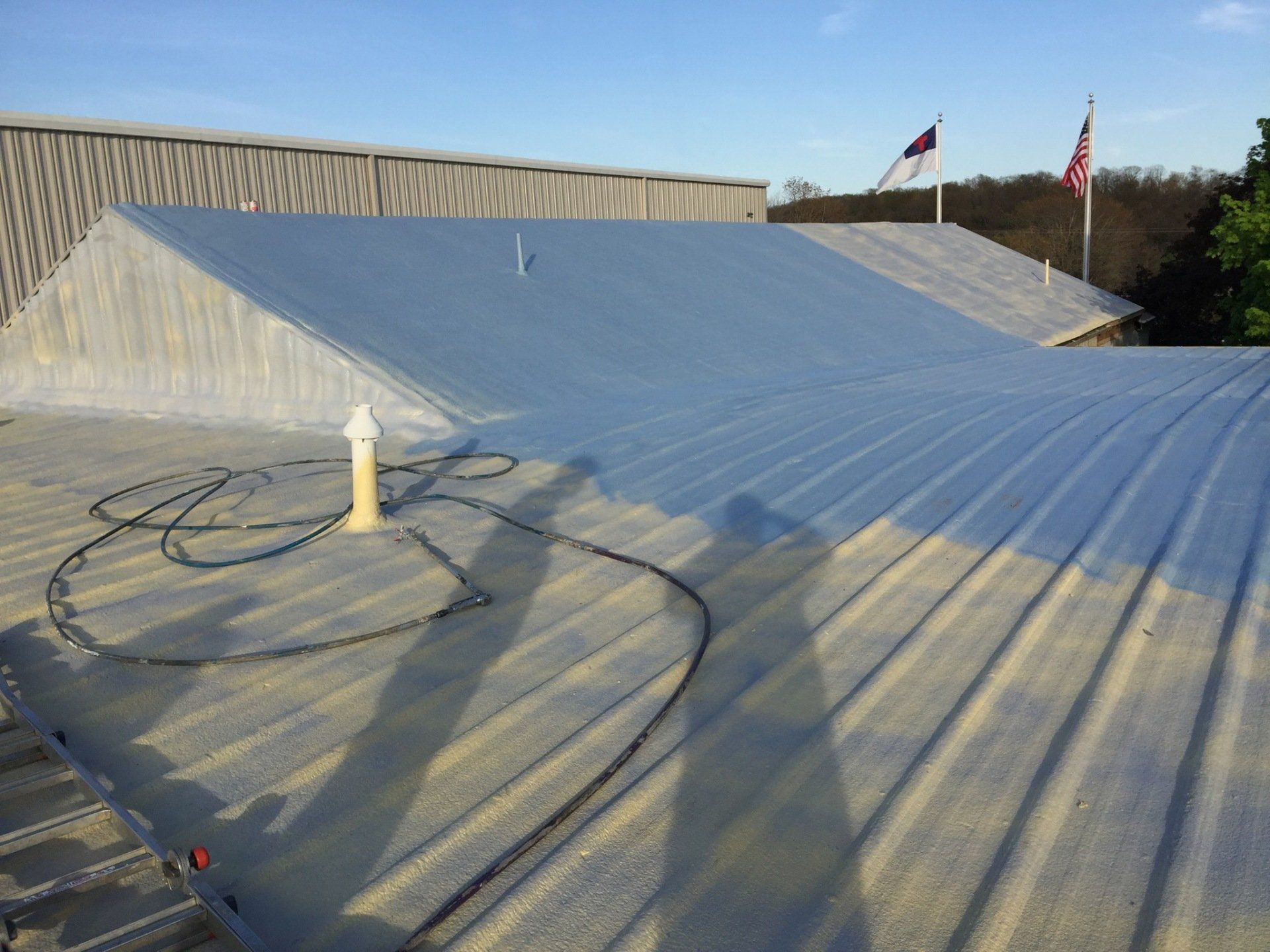 The roof of a building is being painted with a hose.