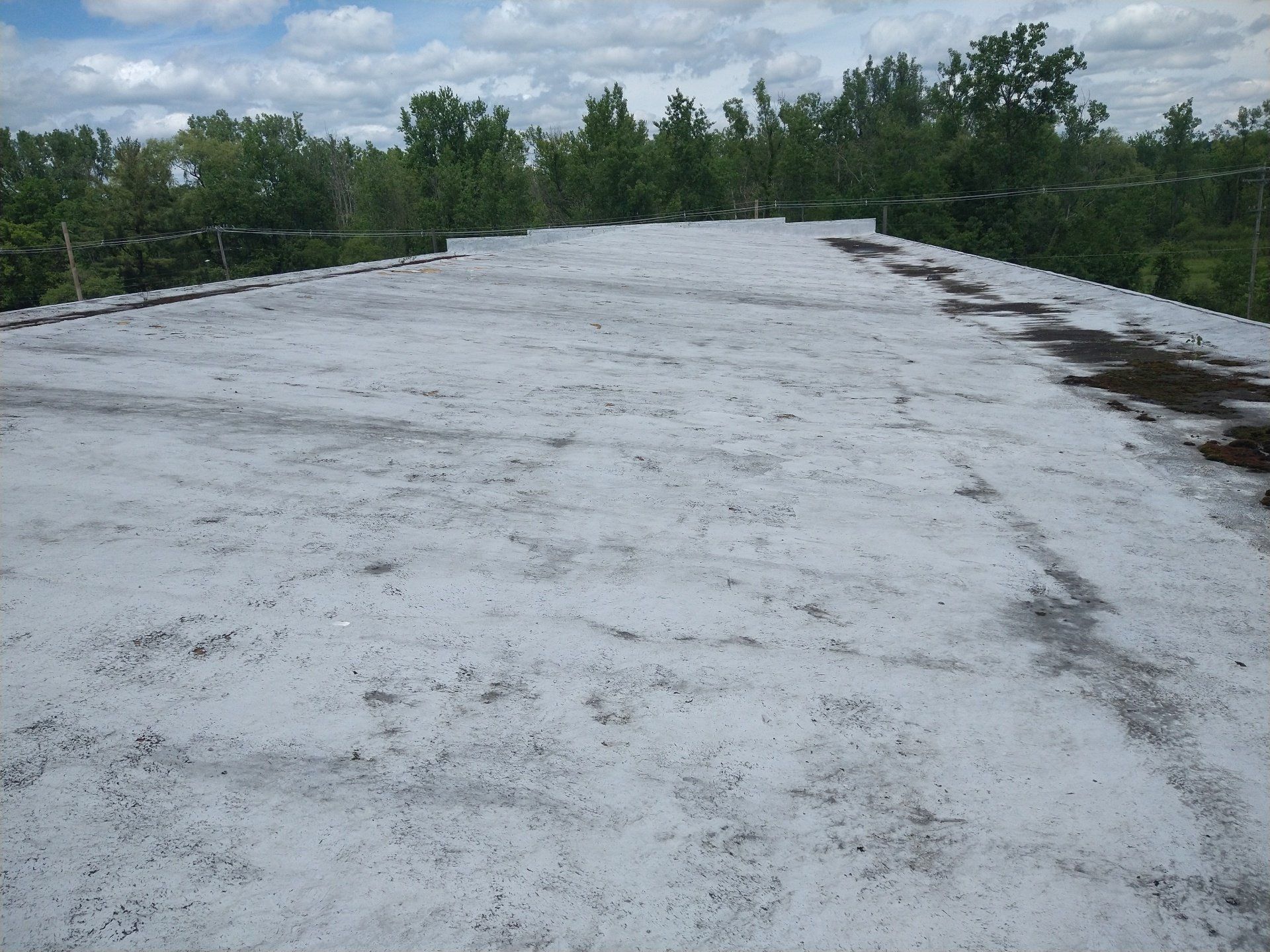 A roof with a lot of snow on it and trees in the background