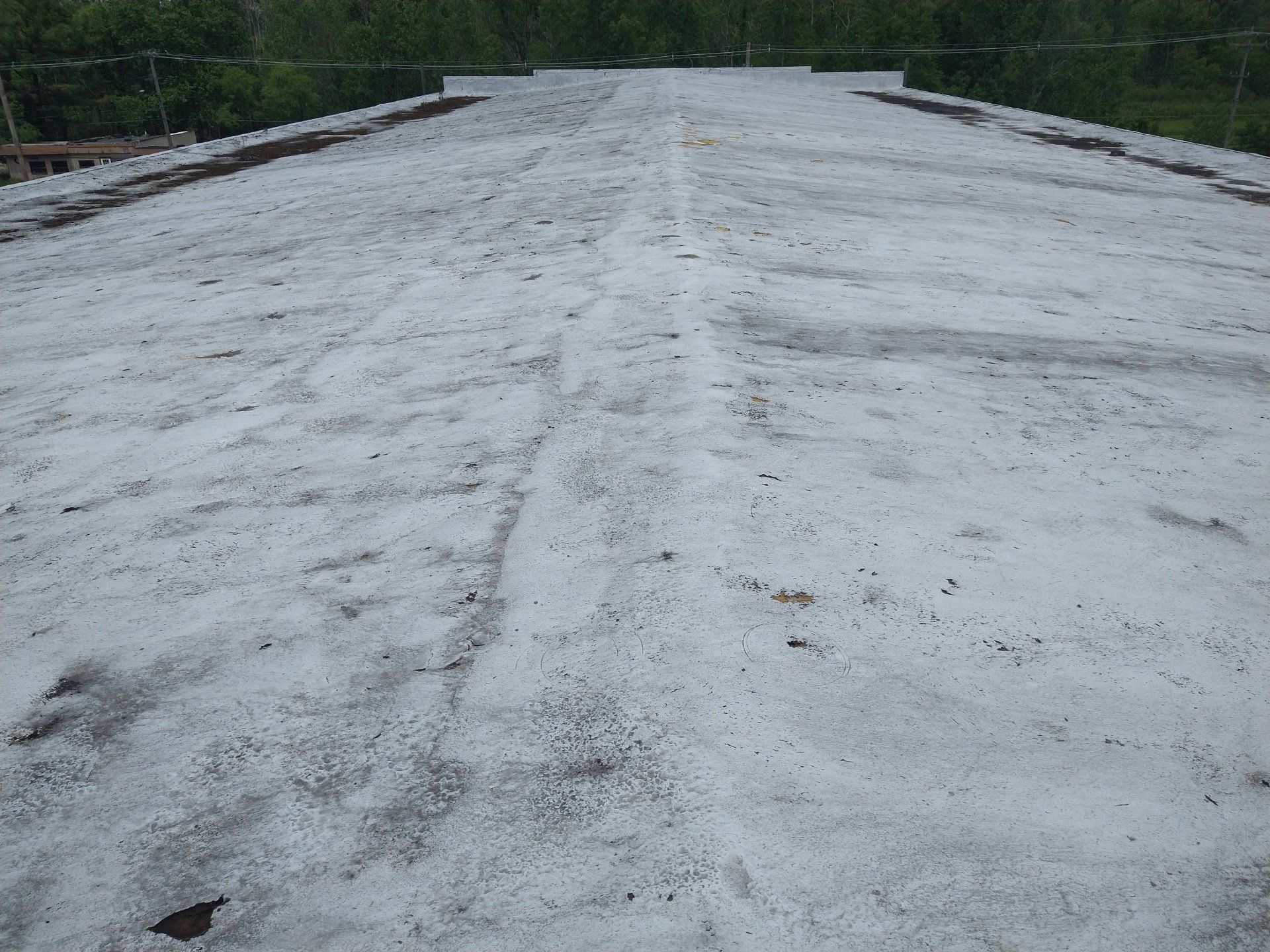 A roof with a lot of snow on it and trees in the background.