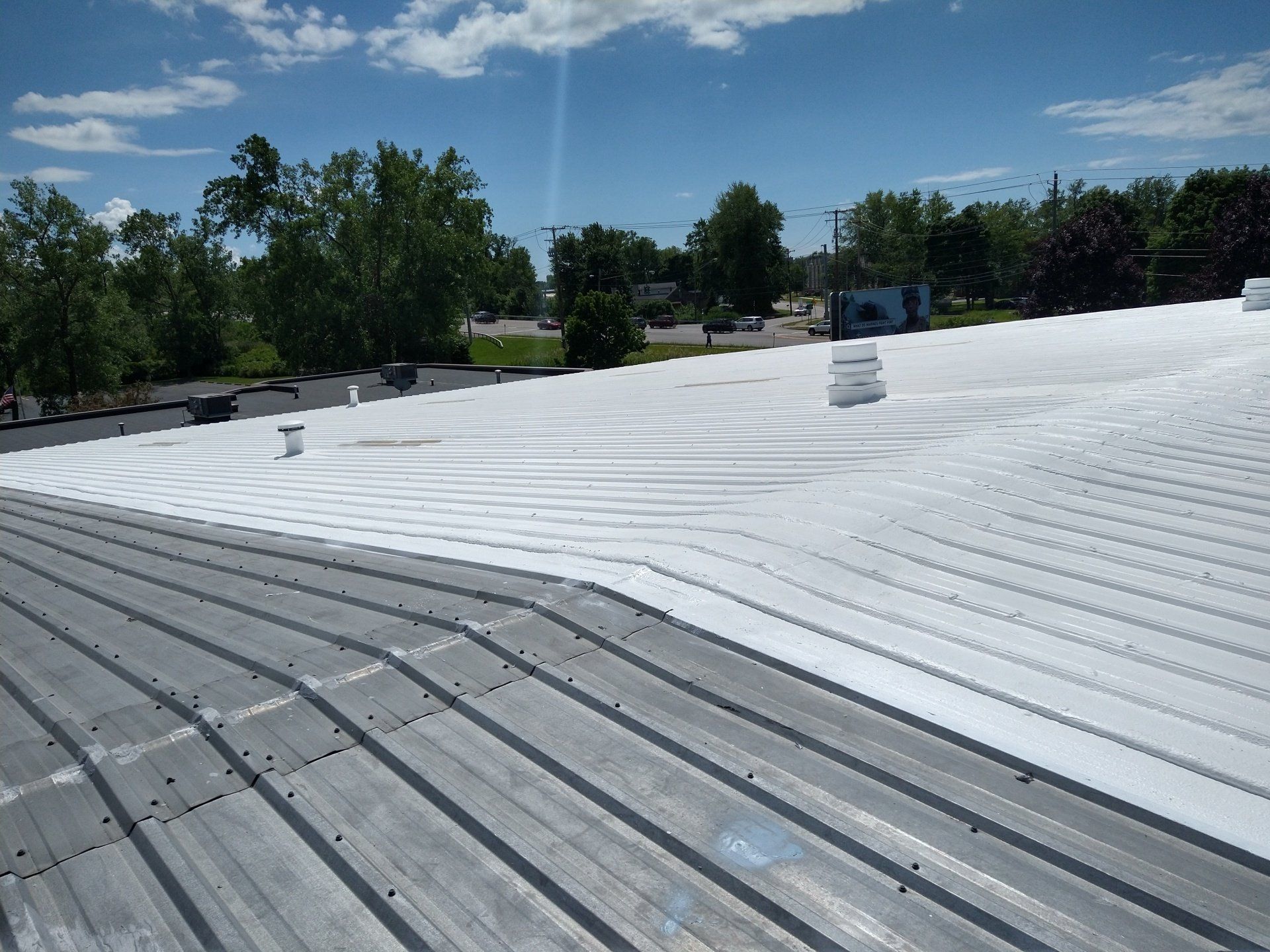 A roof that has been painted white with trees in the background