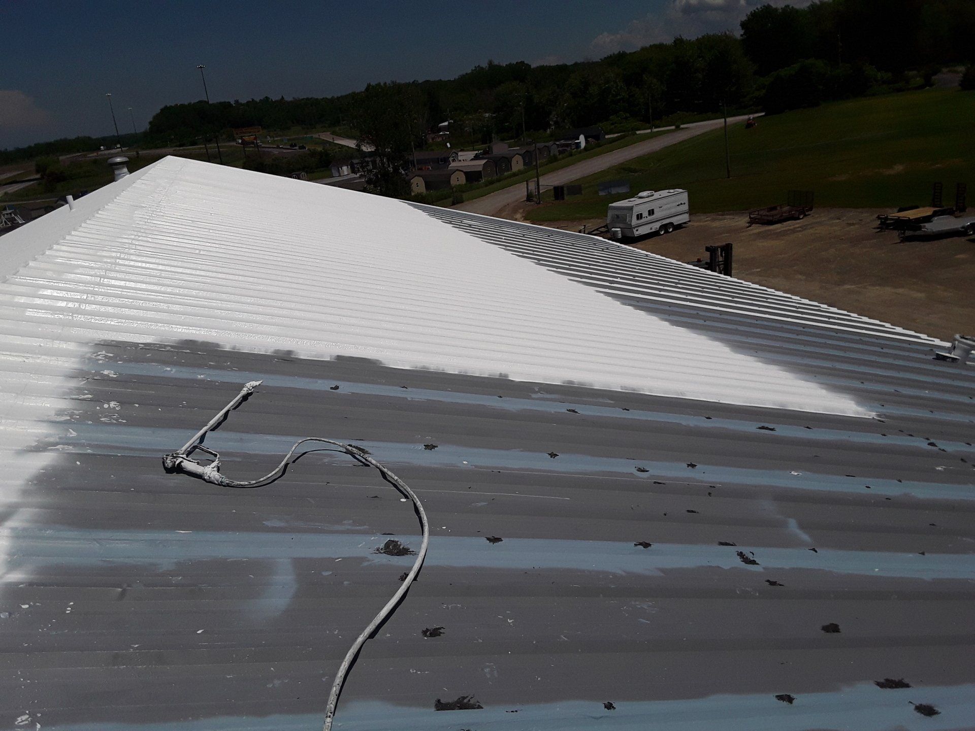 A roof is being painted with white paint.