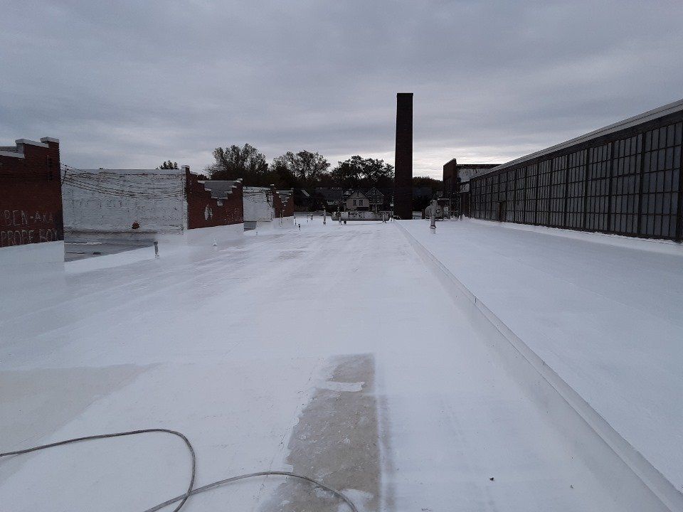The roof of a building is covered in snow and there is a chimney in the background.