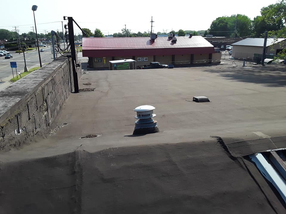 A roof with a chimney on it and a building in the background.