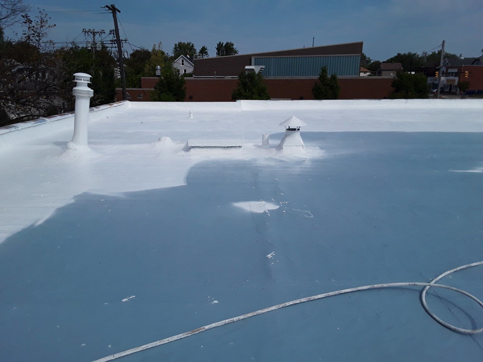 A white roof is being painted on a building.