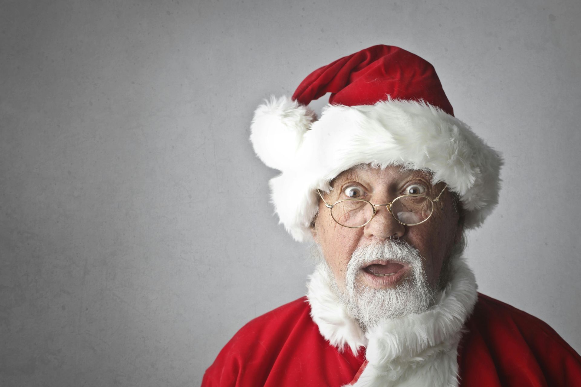 Santa Claus with surprised expression, wearing red suit and hat, glasses, and white beard.