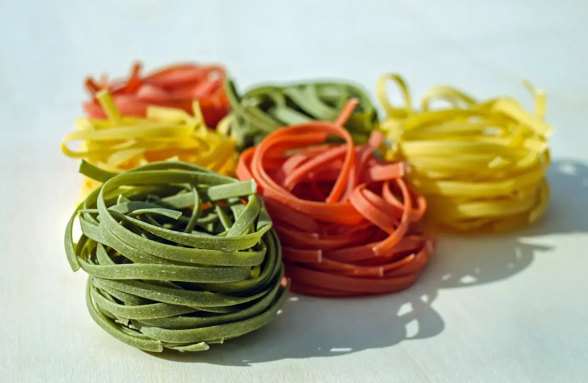 un mucchio di pasta colorata su un tavolo bianco .