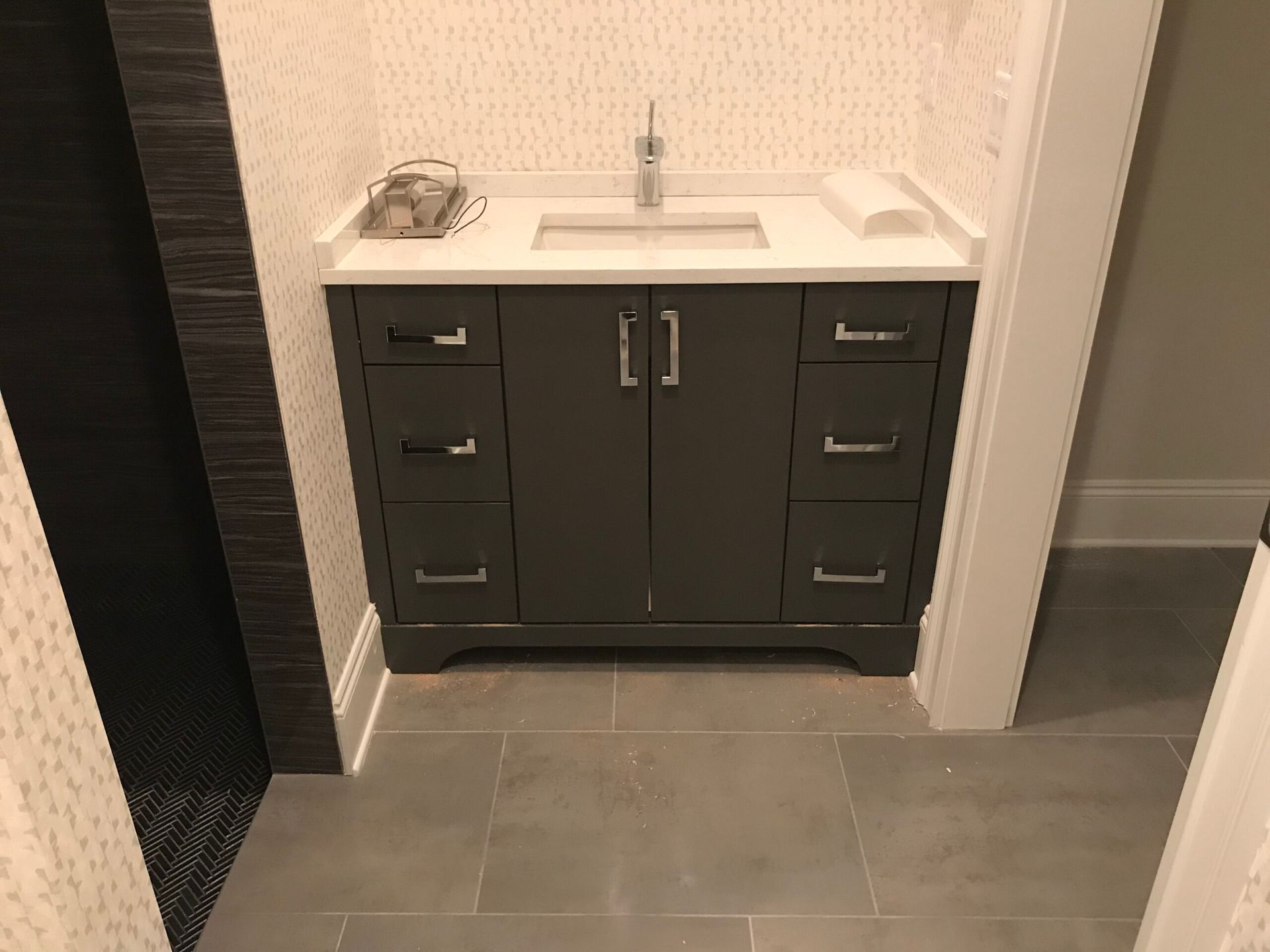 A bathroom with a long sink and drawers and a white counter top.