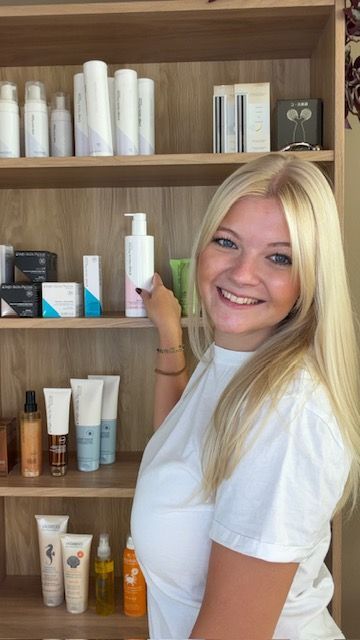 Eine Frau in einem schwarzen Tanktop lächelt in die Kamera.