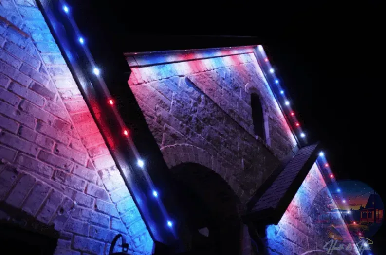 Building facade illuminated with red, white, and blue lights against a dark sky.