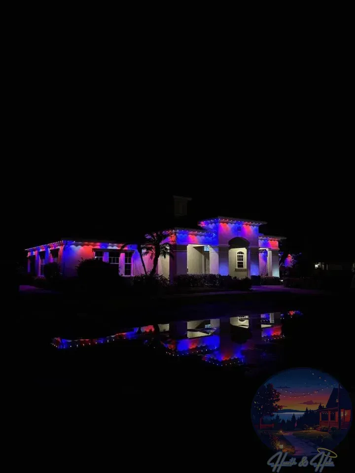 House illuminated with red and blue lights, reflected in a dark body of water at night.