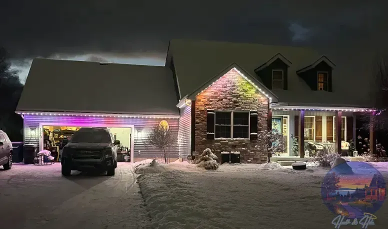 Snowy house at night with colorful lights. Garage door is open with a black truck inside.