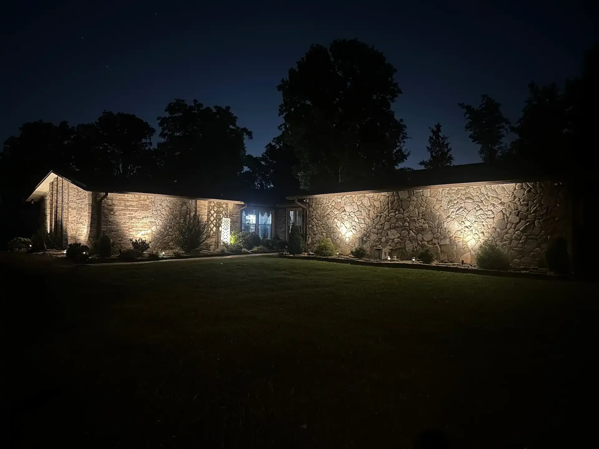 Stone house exterior illuminated at night with spotlights.