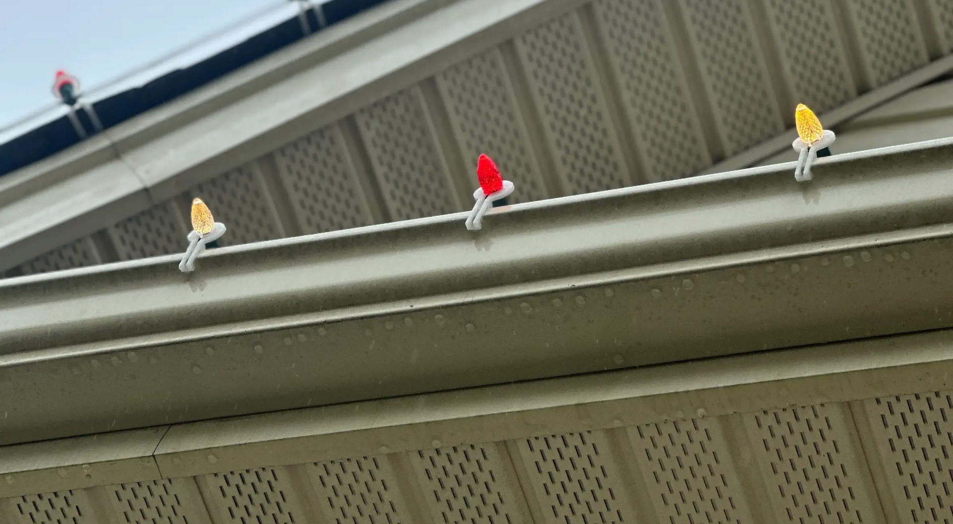Yellow and red bird-shaped decorations clipped to a gutter on a house.