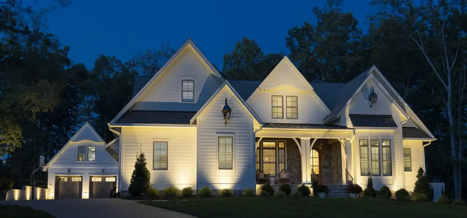 White house at night with outdoor lighting; dark blue sky.