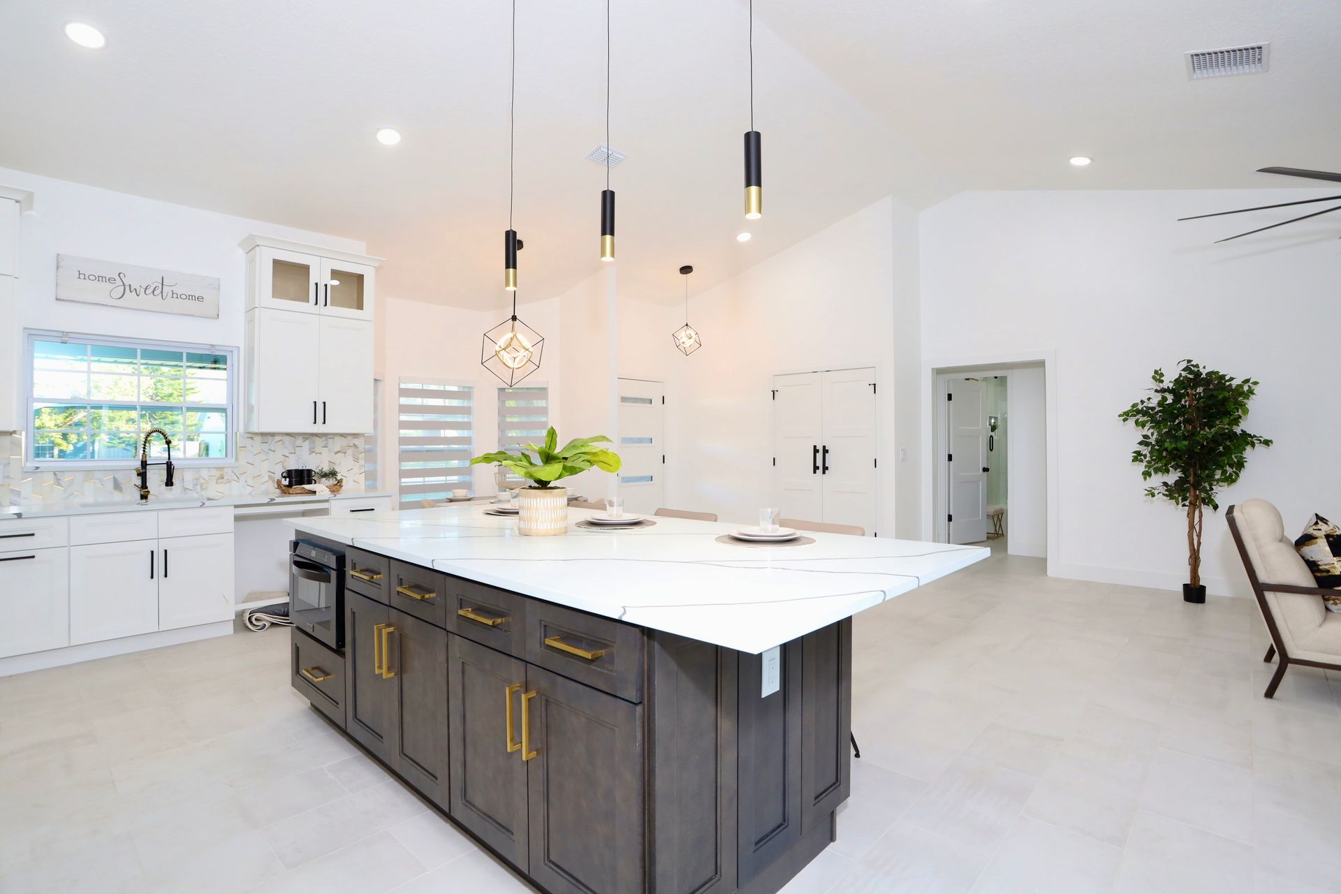 Bright modern white kitchen with central island, stainless appliances, pendant lights, and hardwood floors