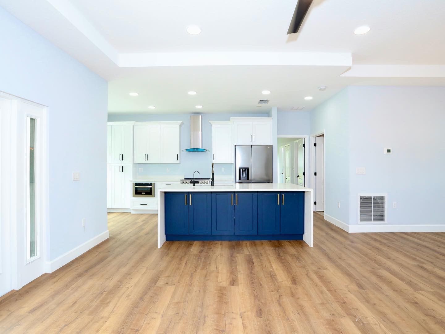 Open-plan modern kitchen and living room with gray island stools, pendant lights, and dark wood floors