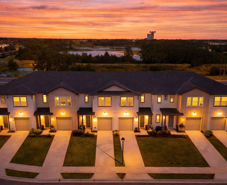 Row of lit townhouses at dusk under a colorful sunset sky, champions gate townhome for sale , short term rental 