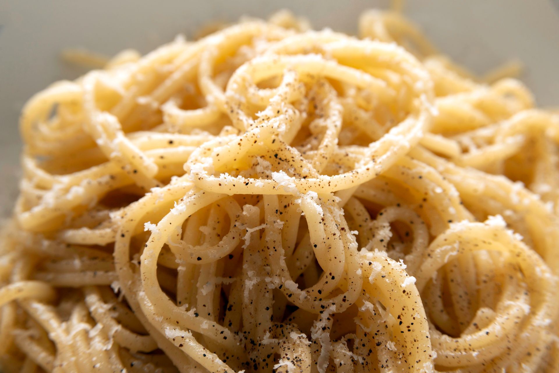 Primo piano di spaghetti con formaggio grattugiato e pepe nero su un piatto
