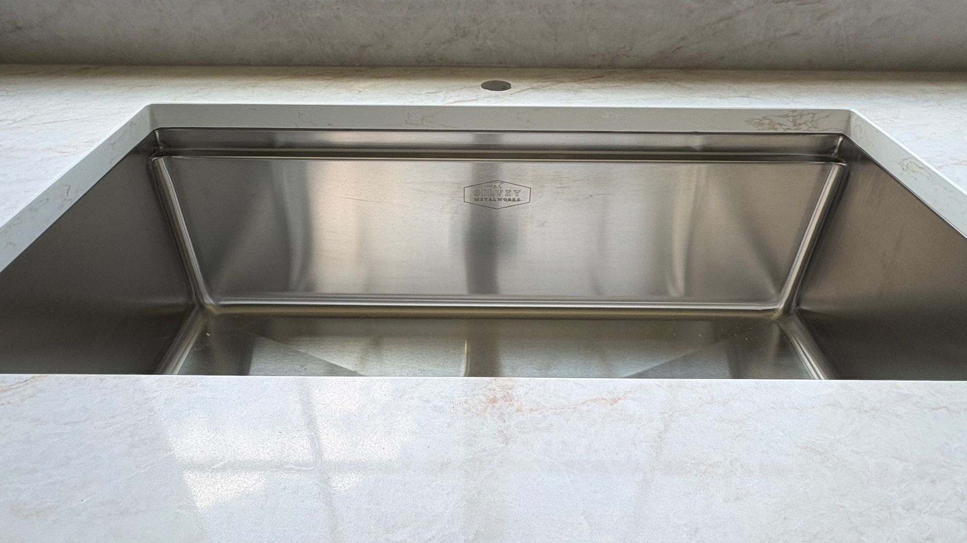 Stainless steel kitchen sink with deep basin and glossy white countertop surround