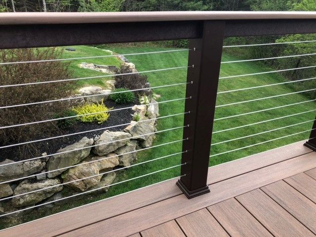 Wooden deck railing overlooking a landscaped stone garden and green lawn