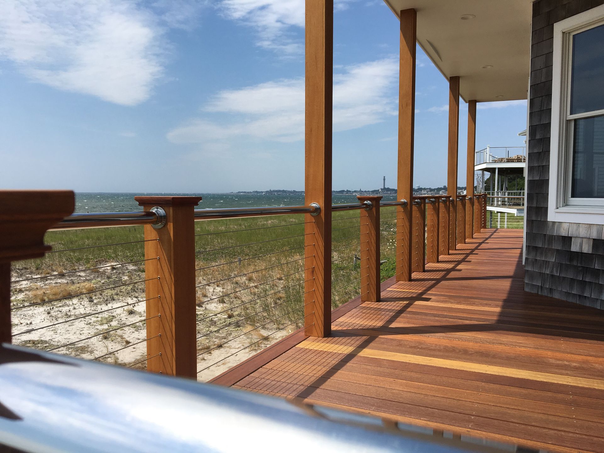 Wooden deck overlooking the ocean and sandy dunes under a blue sky
