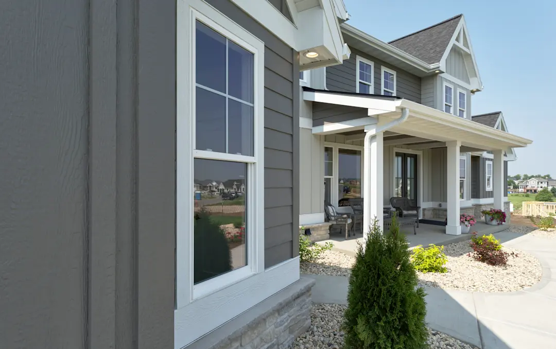 Gray house exterior with white trim, front porch, and landscaped walkway in daylight