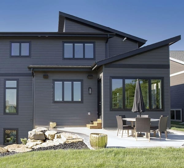 Modern gray two-story house with patio, umbrella table, and landscaped yard