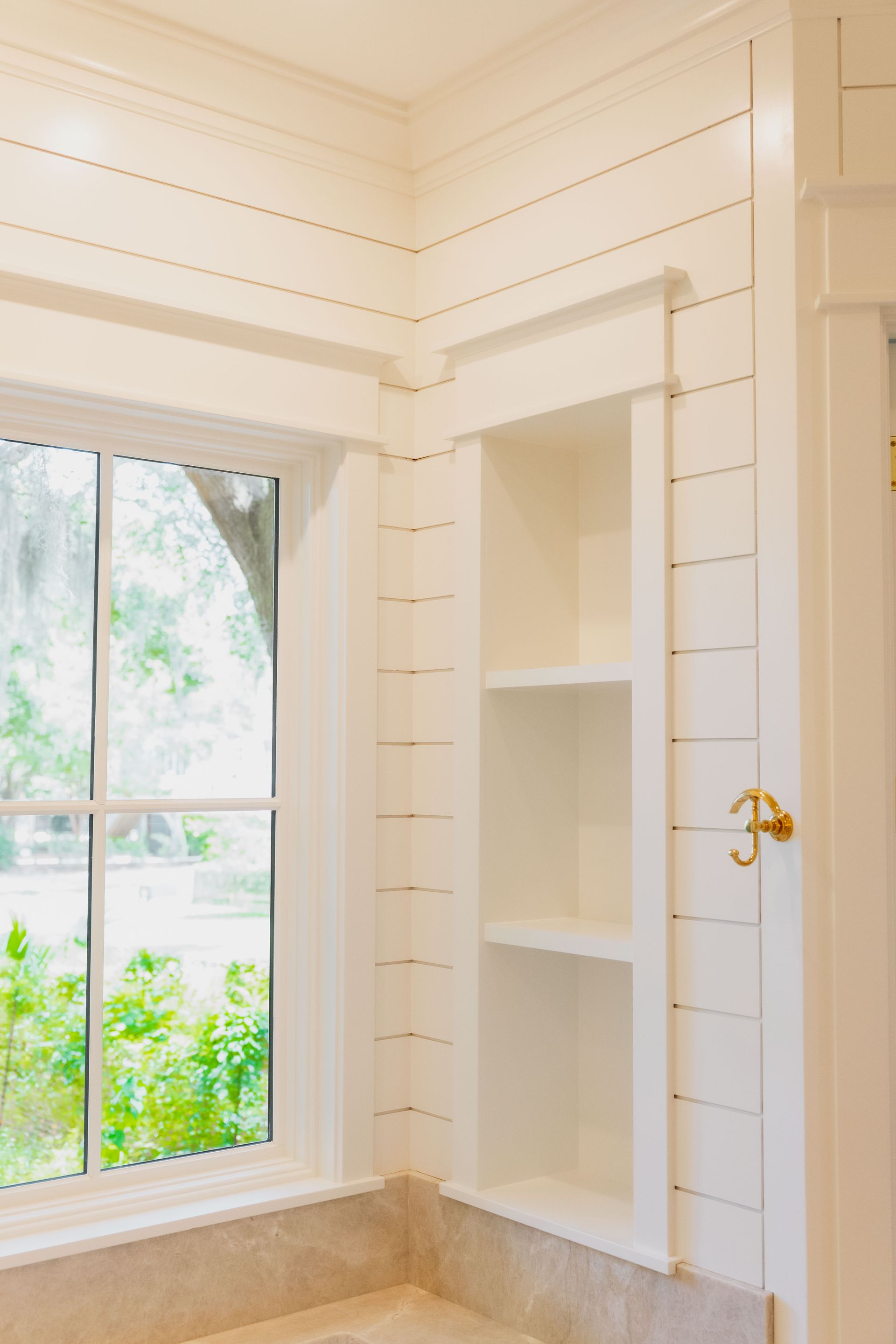 Bright white built-in shelving beside a window in a sunlit room