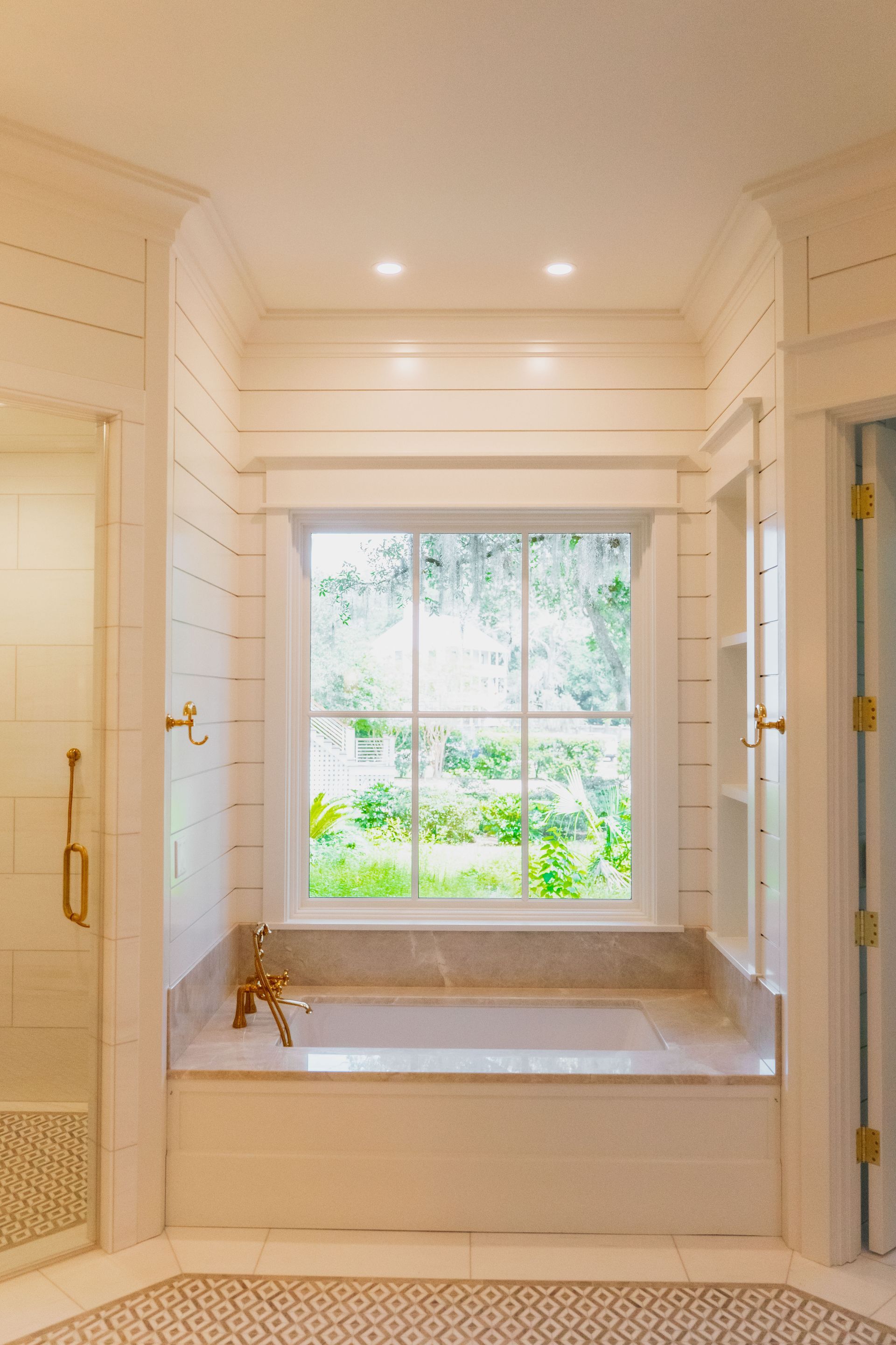 Bright white hallway alcove with a large window seat and built-in cabinets, lit by recessed ceiling lights.