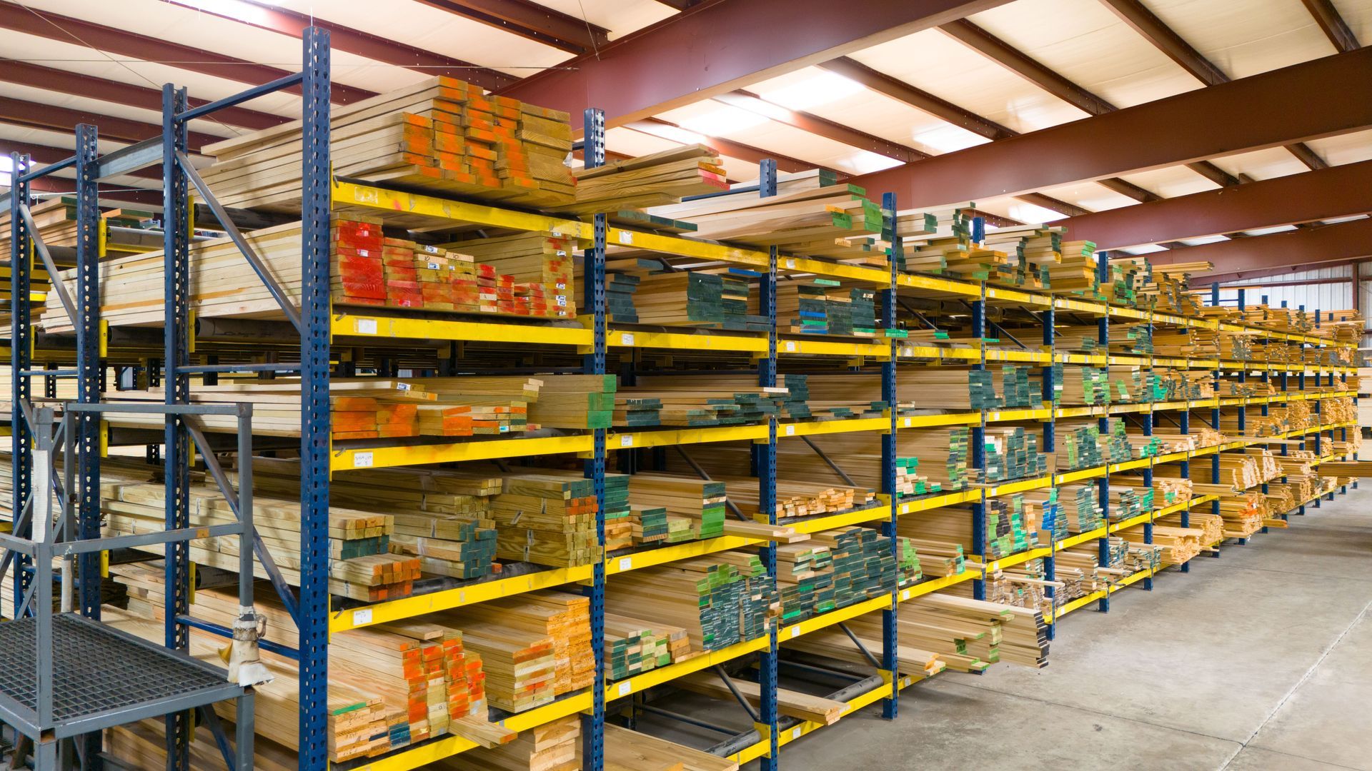 Warehouse aisle with tall metal shelving stocked with yellow packaged goods and boxes