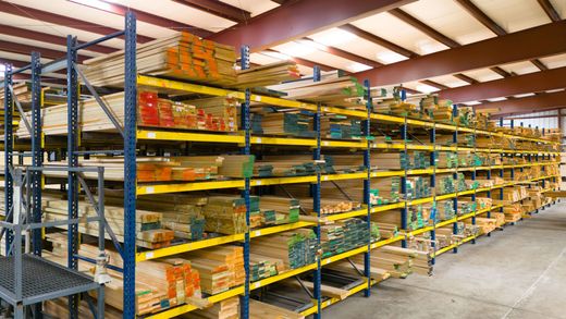 Warehouse aisle with tall metal shelving stocked with yellow packaged goods and boxes