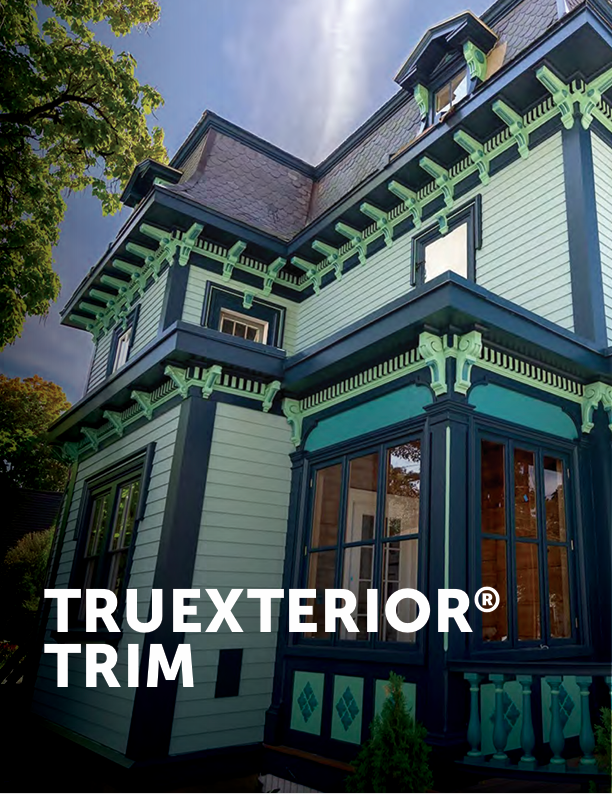 Victorian house exterior with white siding, dark trim, and ornate green accents under a blue sky