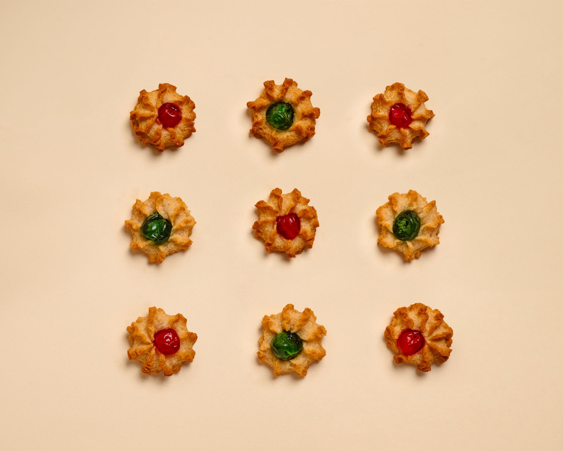 Assortimento di biscotti e pasticcini confezionati in una scatola regalo di marca su sfondo beige.