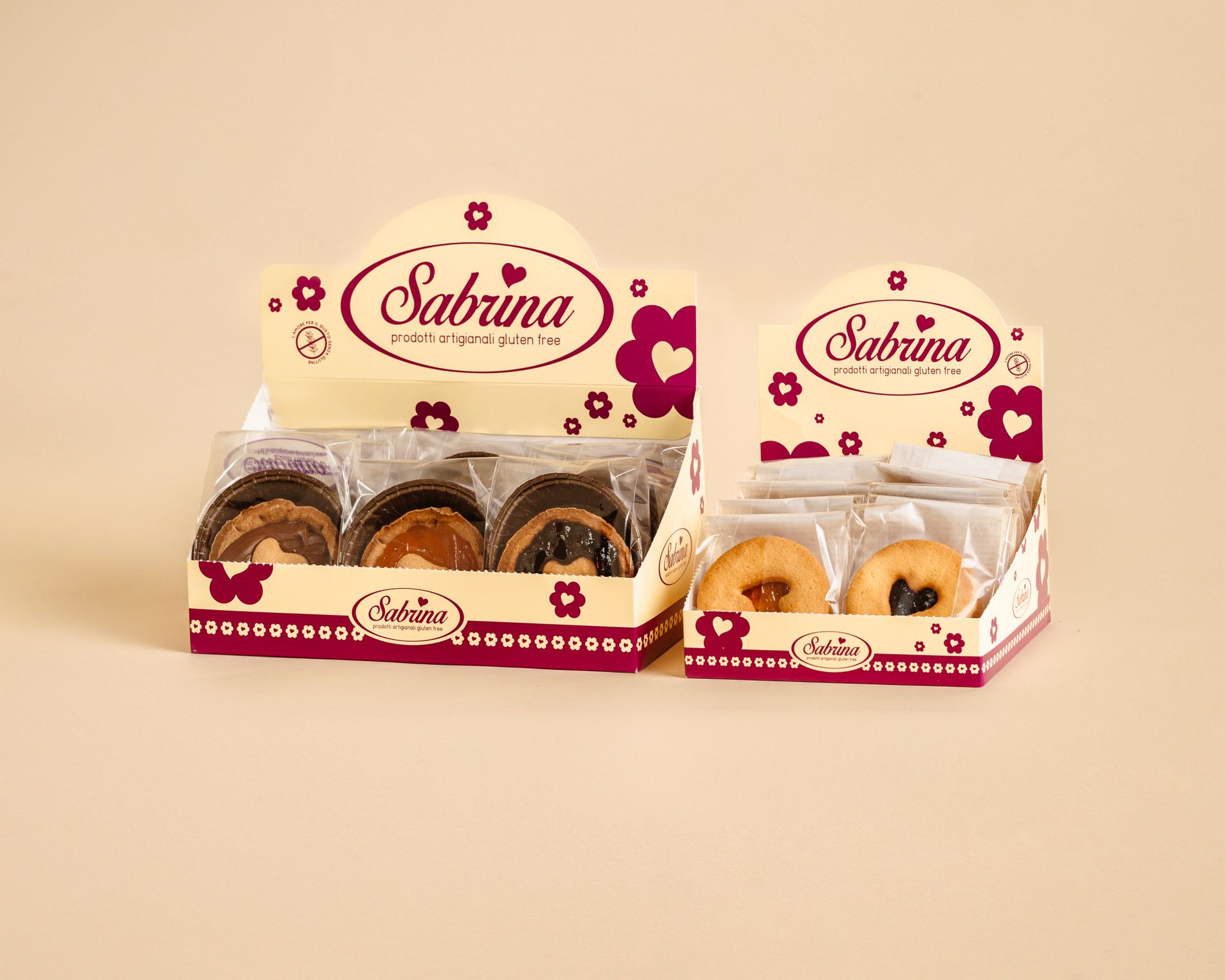 Assortimento di biscotti e pasticcini confezionati in una scatola regalo di marca su sfondo beige.