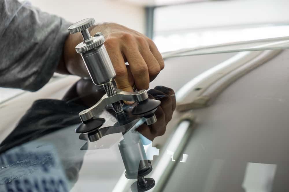 A Man is Repairing a Windshield on a Car With a Machine — Aspire Diesel In Baralaba, QLD