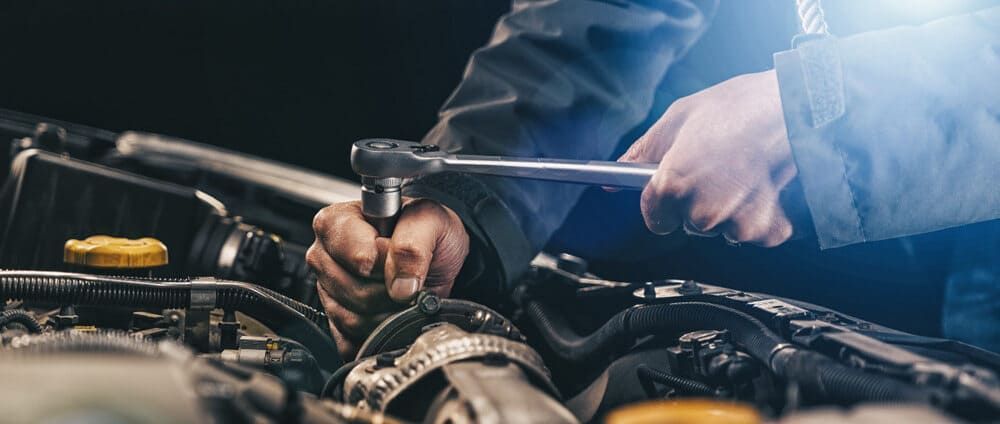 A Man Is Working On A Car Engine With A Wrench — Aspire Diesel In Gracemere, QLD