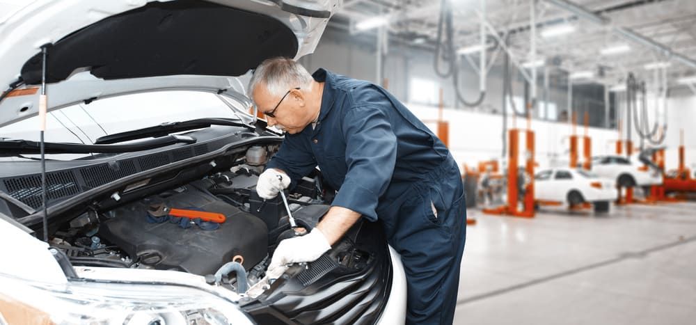 A Mechanic Is Working Under The Hood Of A Car In A Garage — Aspire Diesel In Rockhampton, QLD